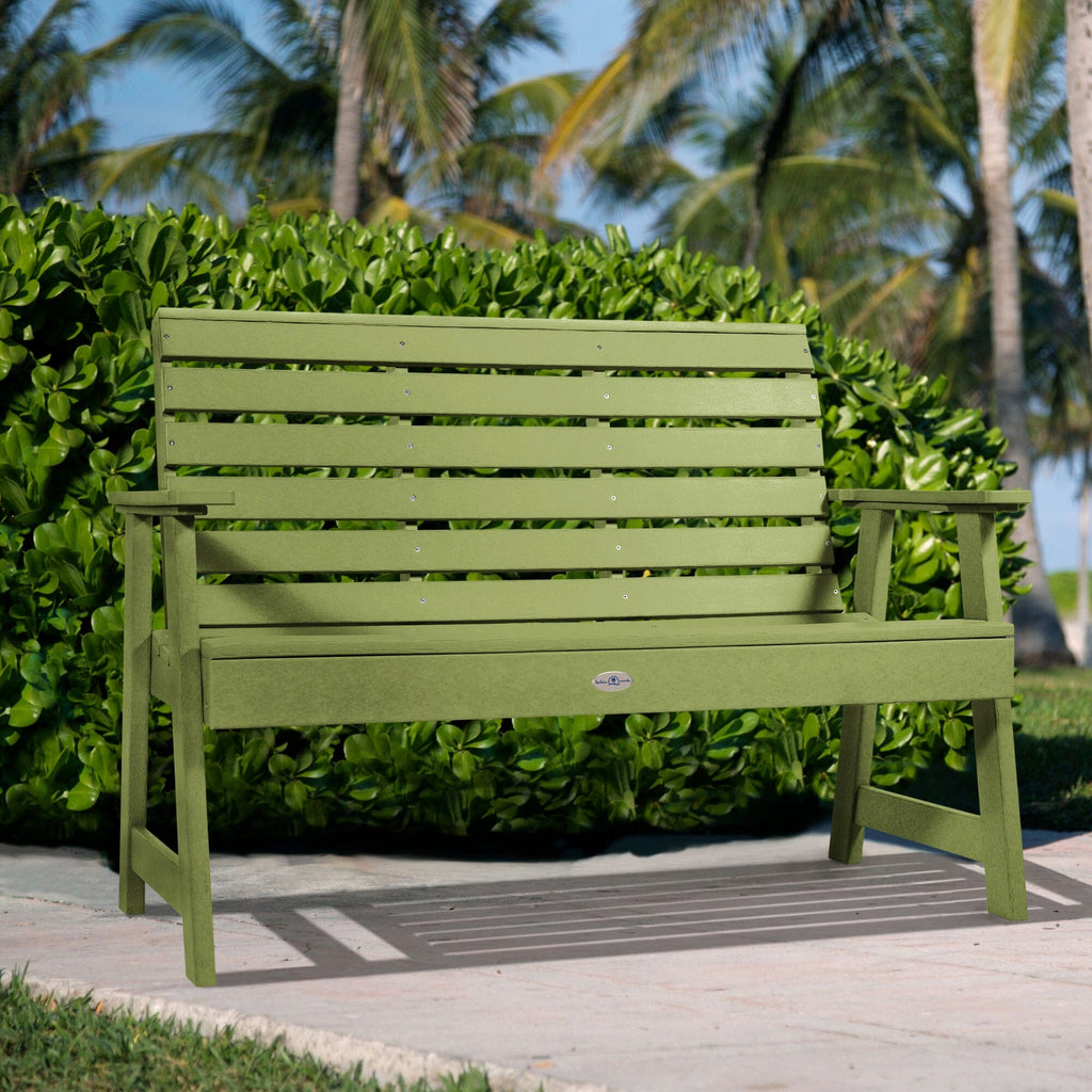 4ft Green Riverside garden bench with palm tree and bush background   