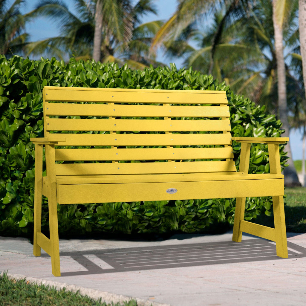 4ft Yellow Riverside garden bench with palm tree and bush background   