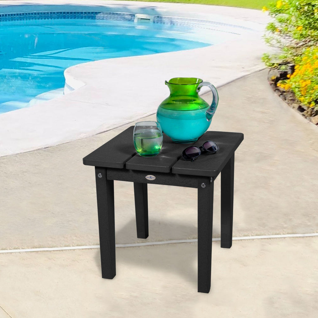 Small black side table with water pitcher and sunglasses