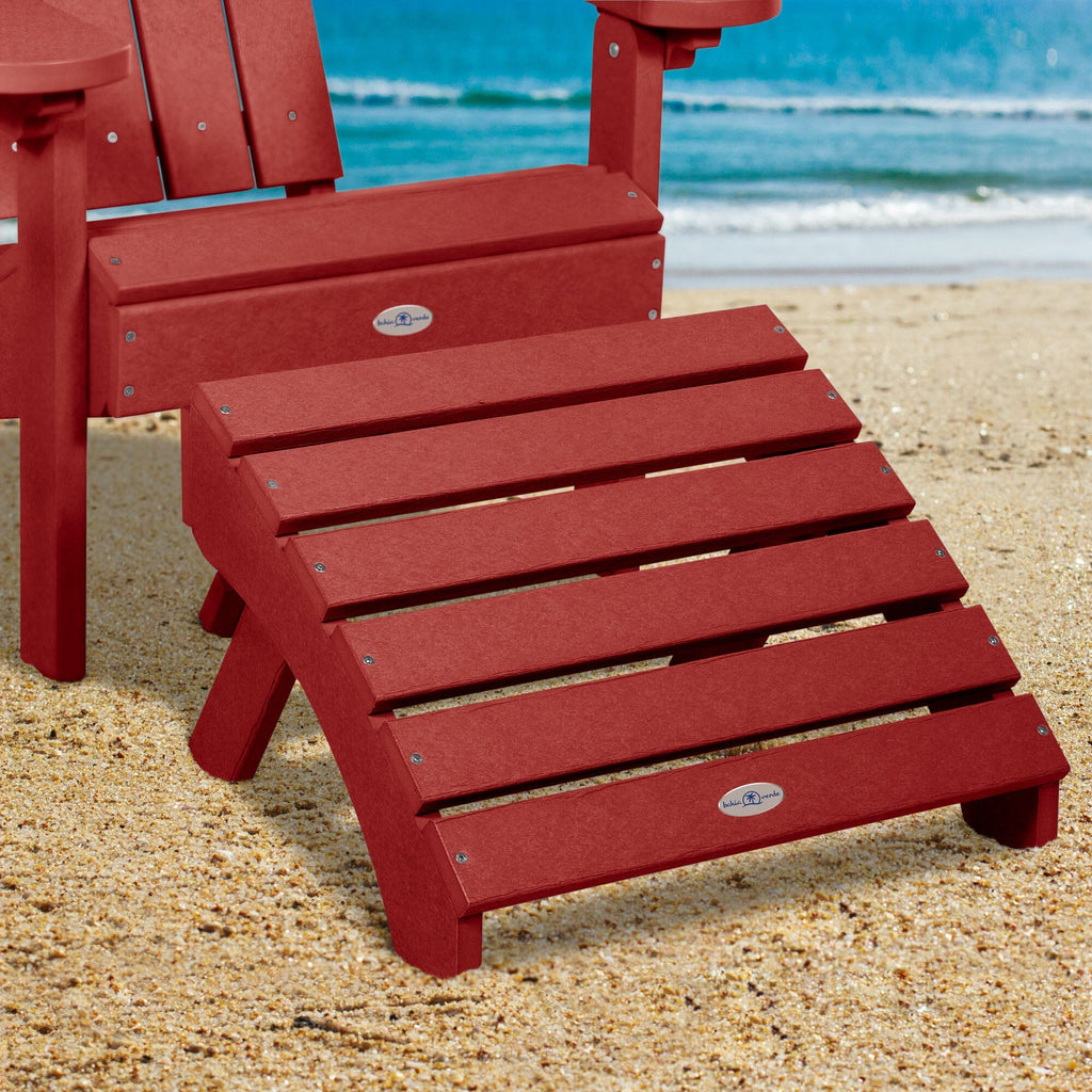 Red Adirondack chair and folding ottoman on a beach 
