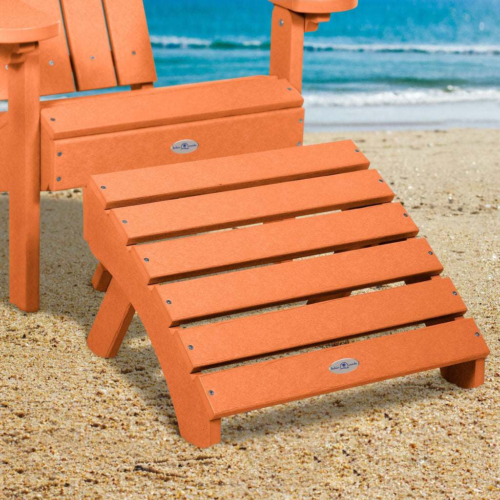 Orange Adirondack chair and folding ottoman on a beach 