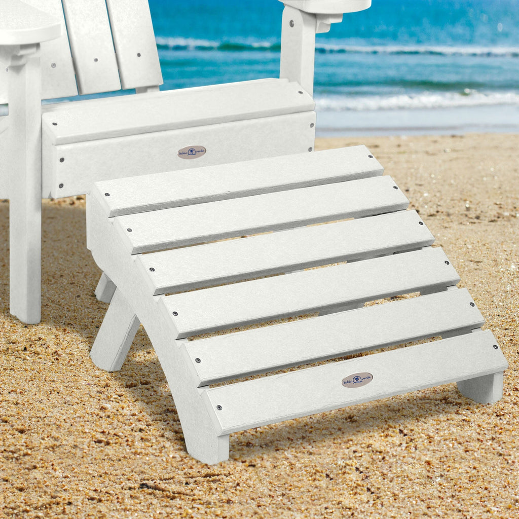 White Adirondack chair and folding ottoman on a beach 
