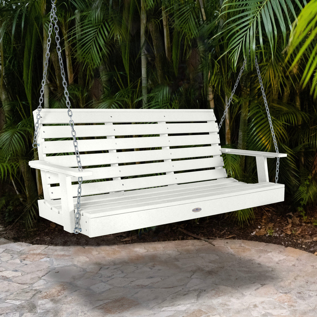 White porch swing with palm background