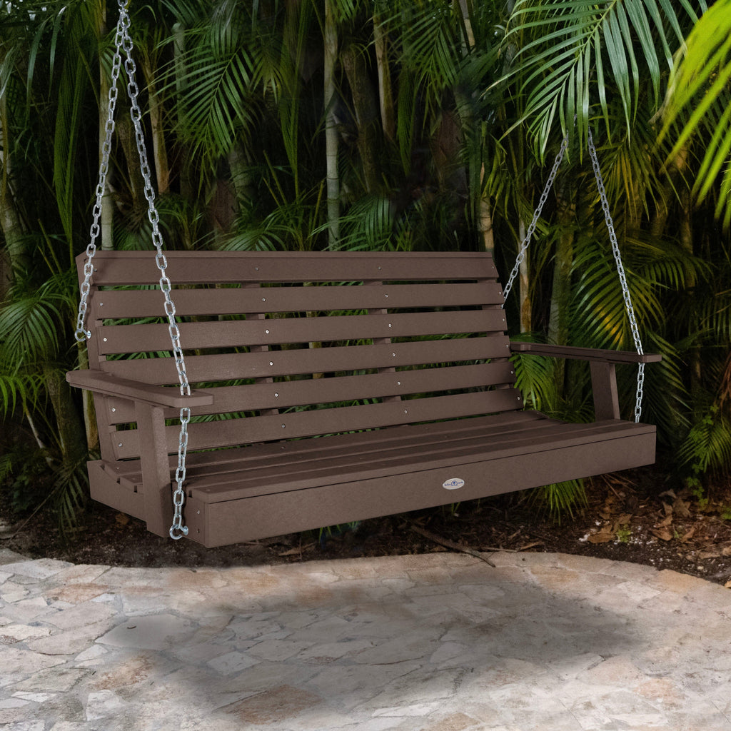 Brown porch swing with palm background.