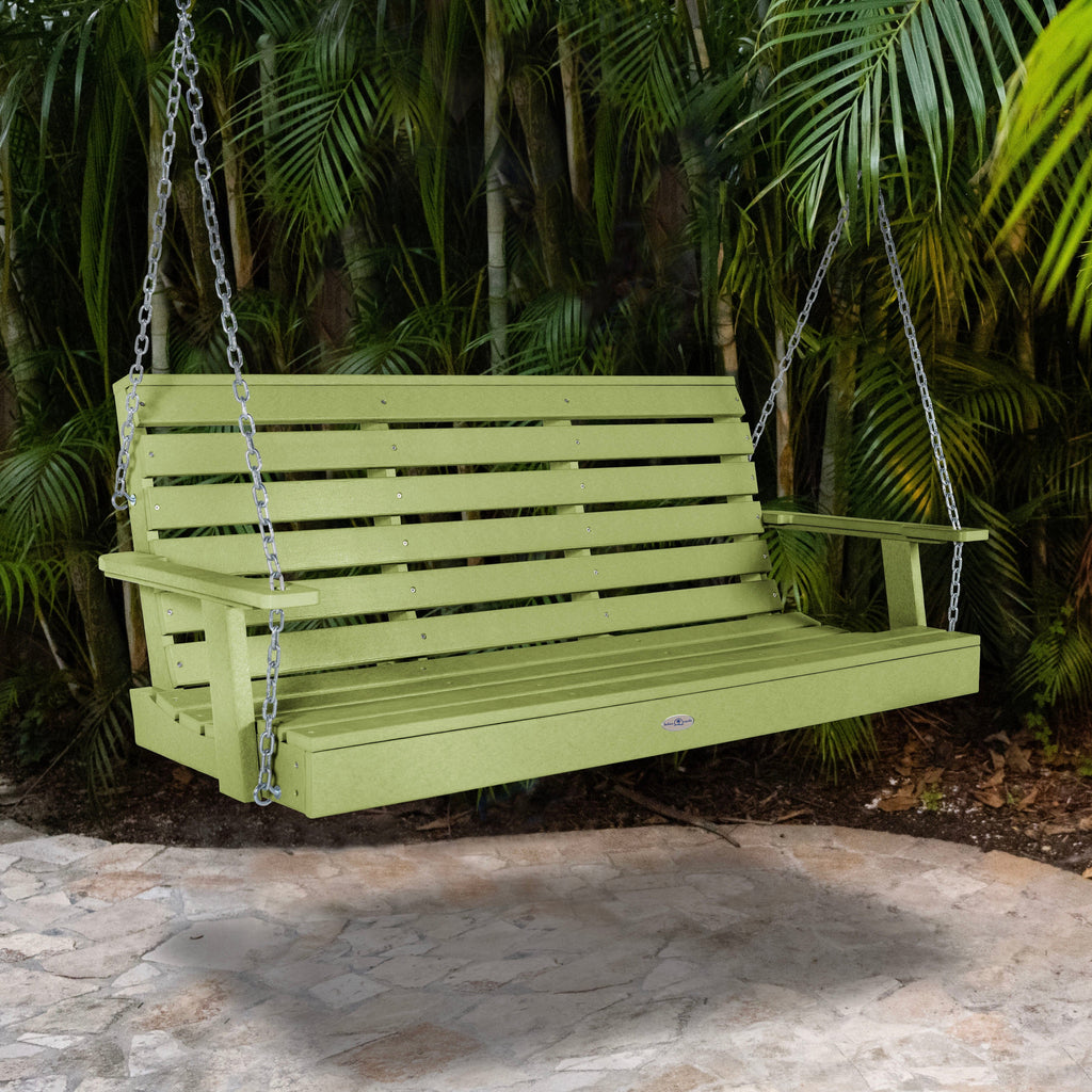 Green porch swing with palm background
