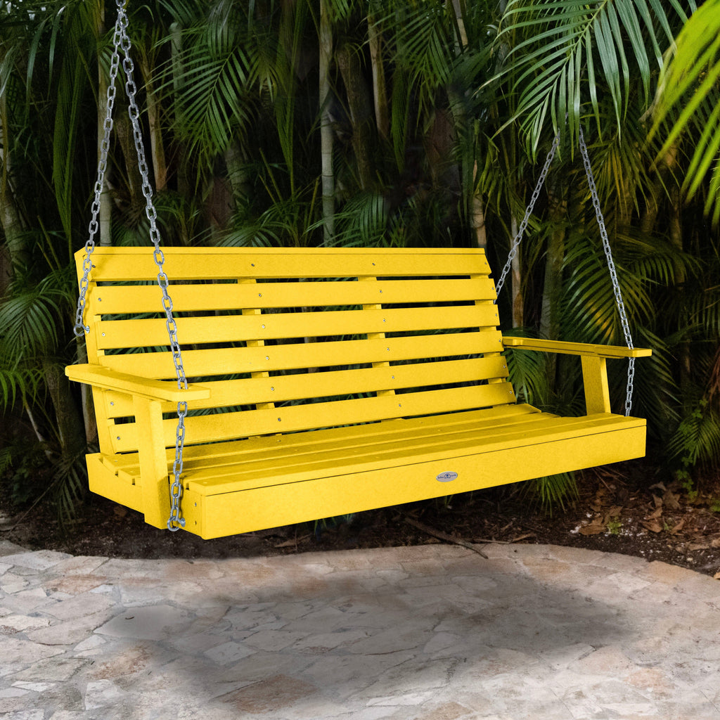 Yellow porch swing with palm background.